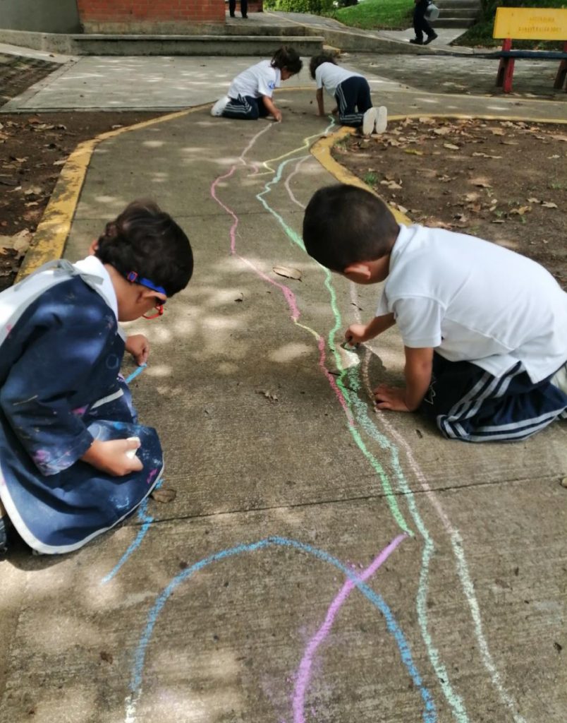 Los niños dibujan un río con tiza